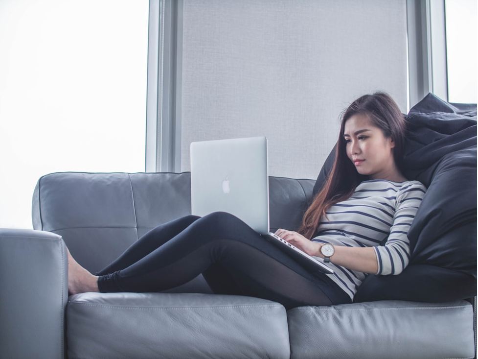 woman sitting on sofa while using MacBook Pro