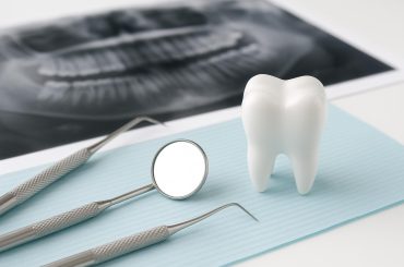 Dental professional examining patient's teeth for early signs affecting cosmetic dental results